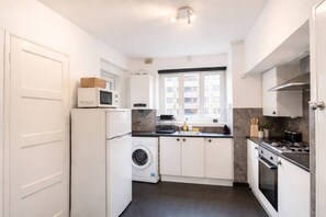 A compact kitchen with a washing machine, microwave, and stove.