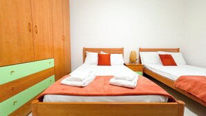 Een hotelkamer met twee eenpersoonsbedden, houten hoofdeinden en een groene accentmuur.