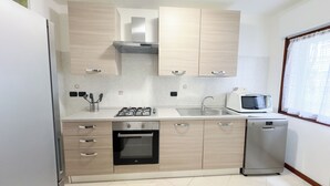 Een kleine keuken met een gasfornuis, magnetron, spoelbak en vaatwasser.