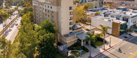 A multi-story hotel with a modern architectural design, featuring a prominent entrance and a rooftop terrace.