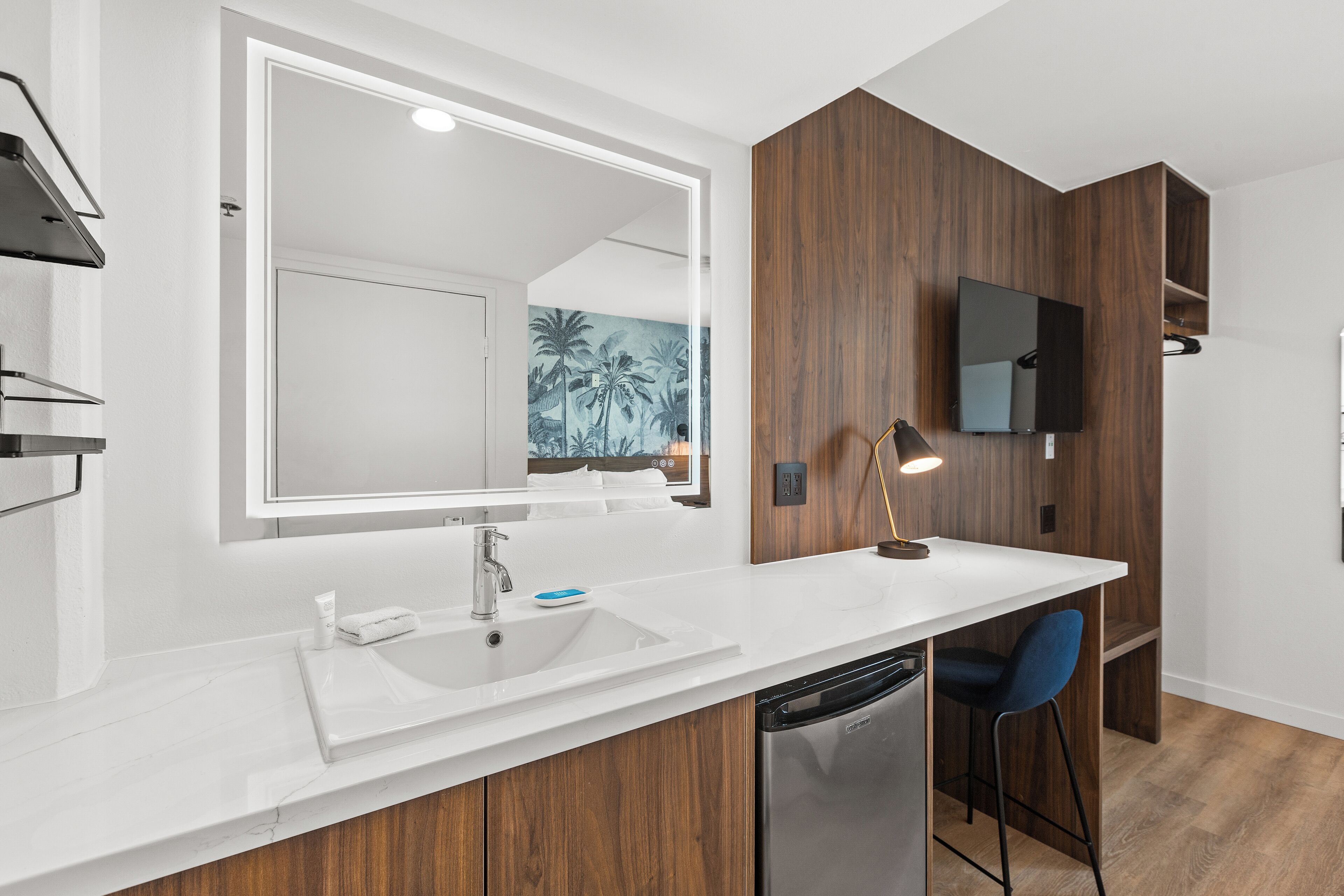 A modern bathroom with a white sink, mirror, and wooden accents.