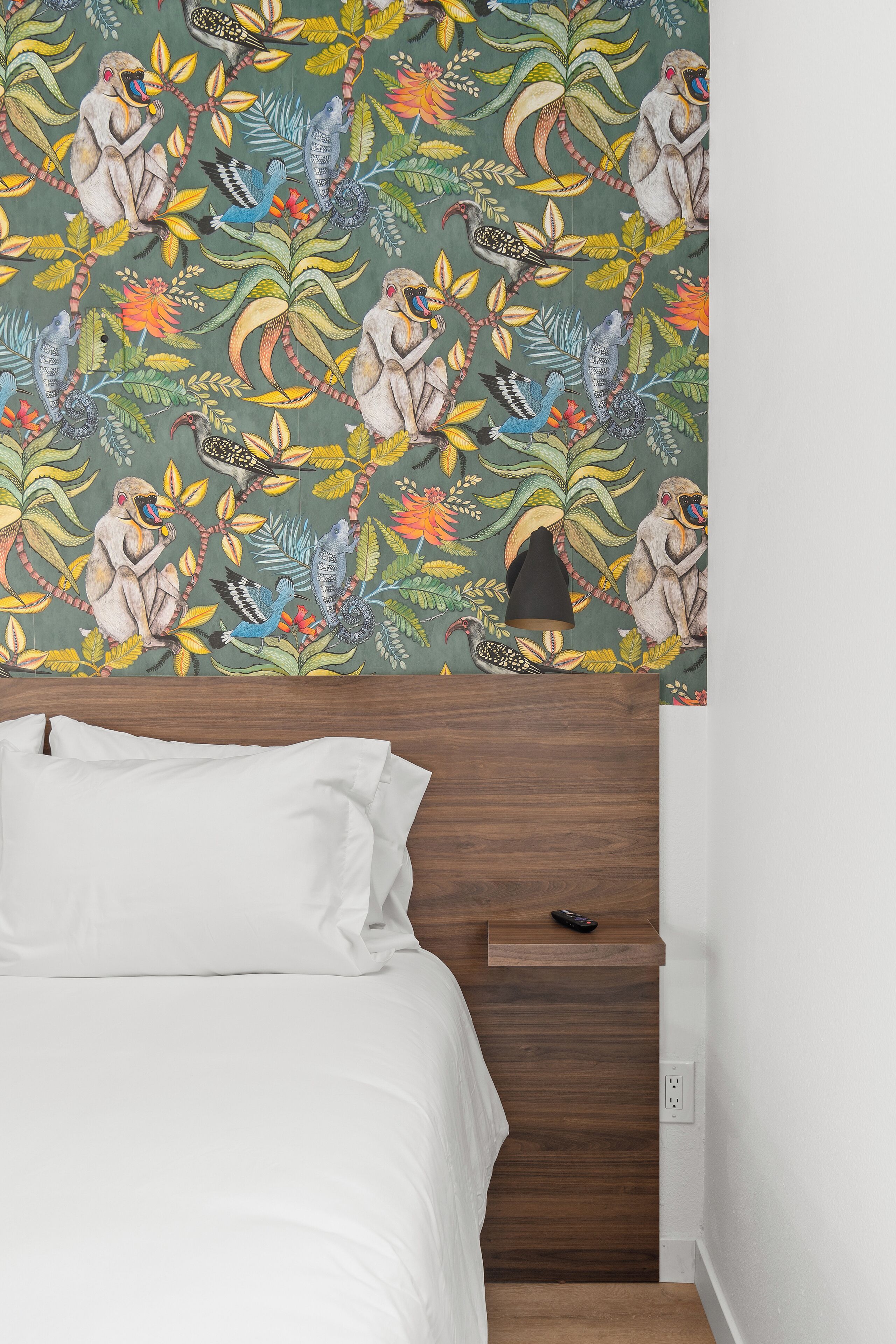 A bedroom with a bed, a nightstand, and a wall with a colorful mural.