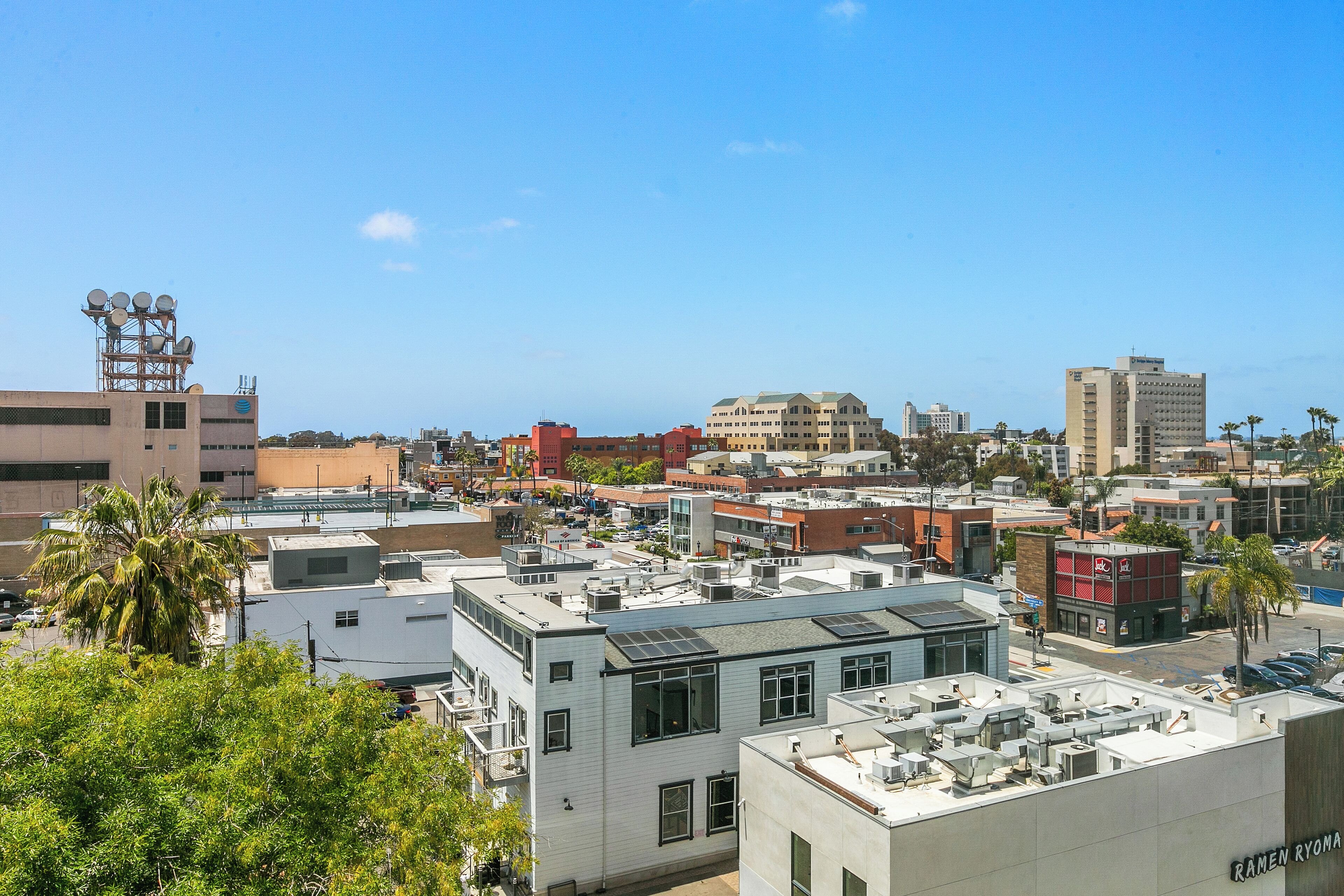 Une vue urbaine avec différents bâtiments, dont un hôtel portant l’enseigne « RAMEN RYOMA ».