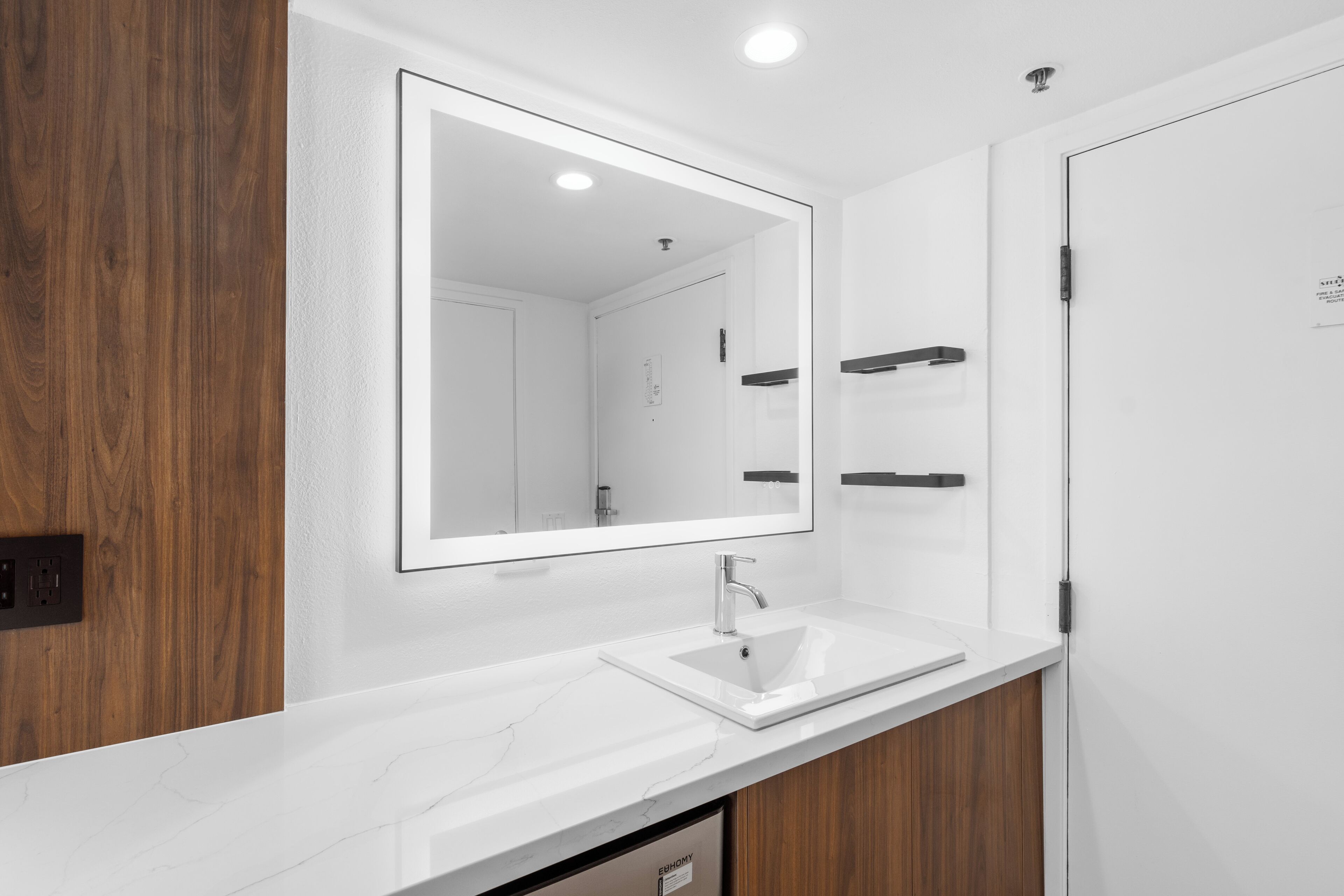 Une salle de bain moderne avec un lavabo blanc, un grand miroir et des meubles en bois.
