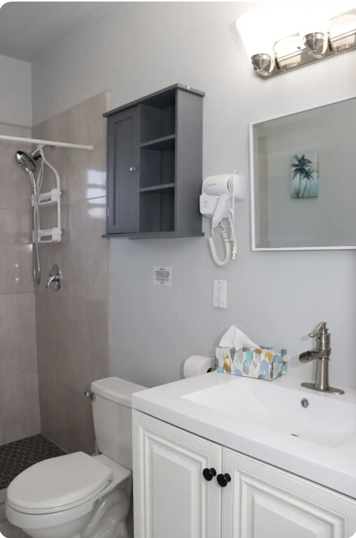 A bathroom with a toilet, sink, and shower. There is a cabinet above the sink and a towel rack on the wall.