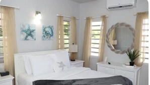 A bedroom with a bed, bedside tables, a mirror, and artwork on the wall.