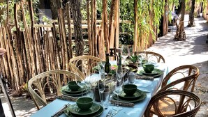 A table set outdoors with wicker chairs, a light blue tablecloth, and green plates. - Refugio 31 (Partido de Tigre)