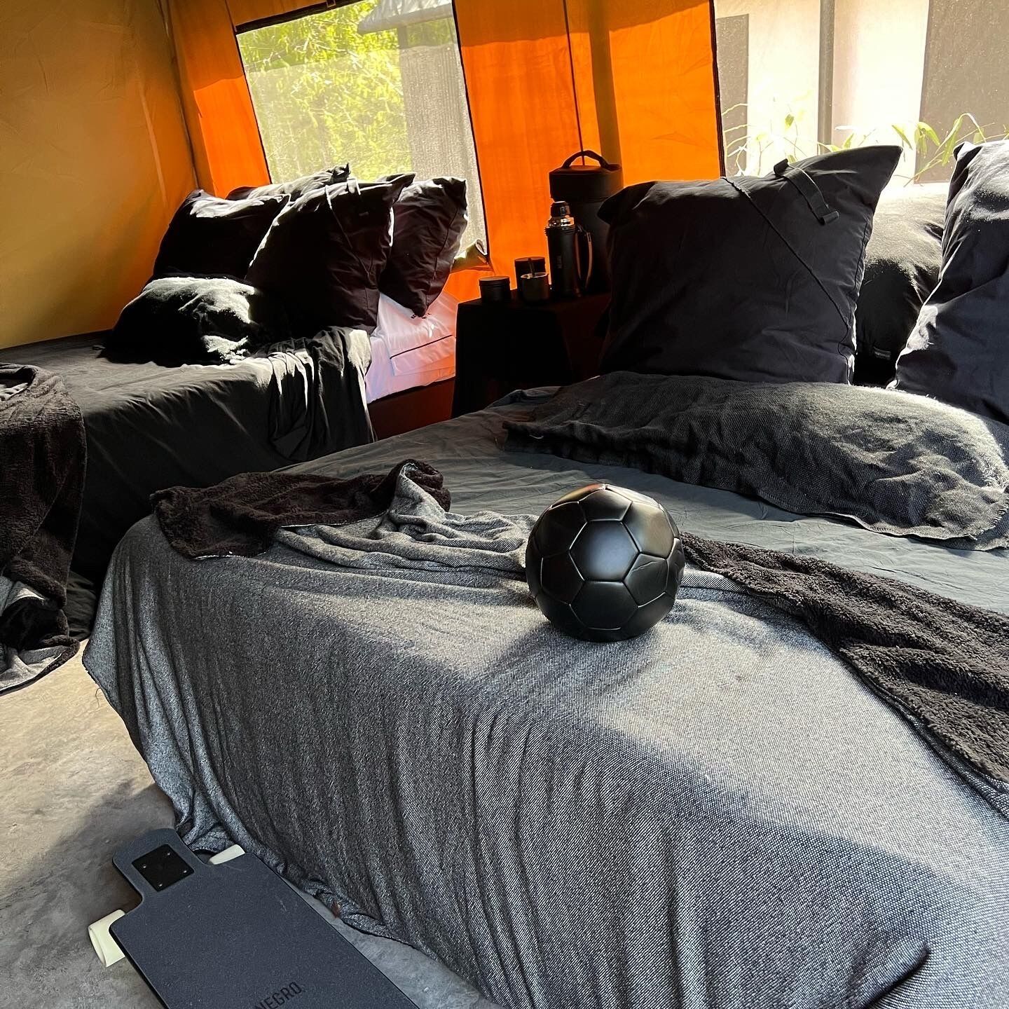 Un dormitorio con dos camas, una ventana con persianas y un balón de fútbol sobre la cama.