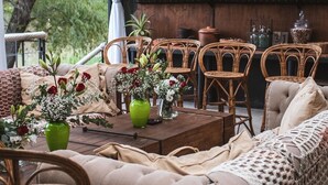 A cozy outdoor seating area with wicker furniture, a wooden bar with glass cabinets, and a view of greenery. - Refugio 31 (Partido de Tigre)