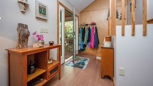 A wooden interior with a rustic decor, a wooden cabinet, a vase with flowers, and a rack with clothes.
