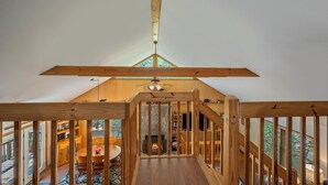 A wooden interior with a view of a dining area and a fireplace.