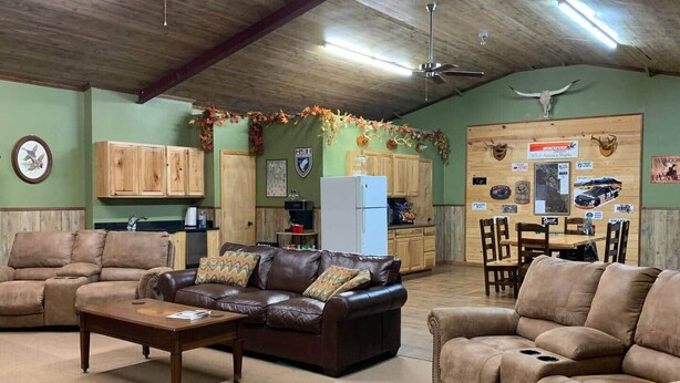 A spacious living room with leather sofas, a coffee table, and a dining area with wooden chairs and a table.