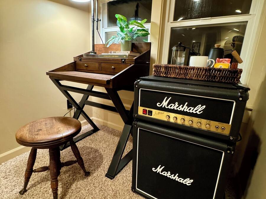 A small room with a wooden table, a stool, and a Marshall amplifier.