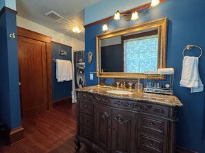 A bathroom with a dark wooden vanity, a large mirror, and a towel rack.