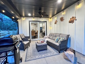 Une terrasse extérieure avec un barbecue, des meubles en osier et un tapis à motifs.