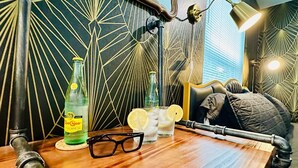 A room with a geometric patterned wall, a bed with a headboard, a table with a bottle, glasses, and a lamp. - 2 Primary EnSuites, HOT Tub, Firepit, Hammock, Min to St Augustine, DOG-Friendly (St. Augustine)