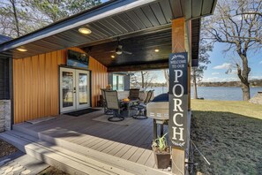 A covered porch with a grill, outdoor furniture, and a sign welcoming guests. - Fire Pit + Dock: Lakefront Cabin in Zimmerman! (Zimmerman)