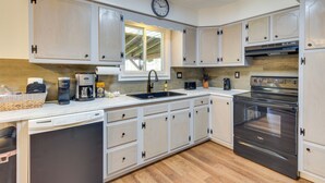A modern kitchen with white cabinets, a built-in oven, a sink, and a clock on the wall. - Cozy DuBois Home w/ Deck ~ 8 Mi to Treasure Lake! (DuBois)