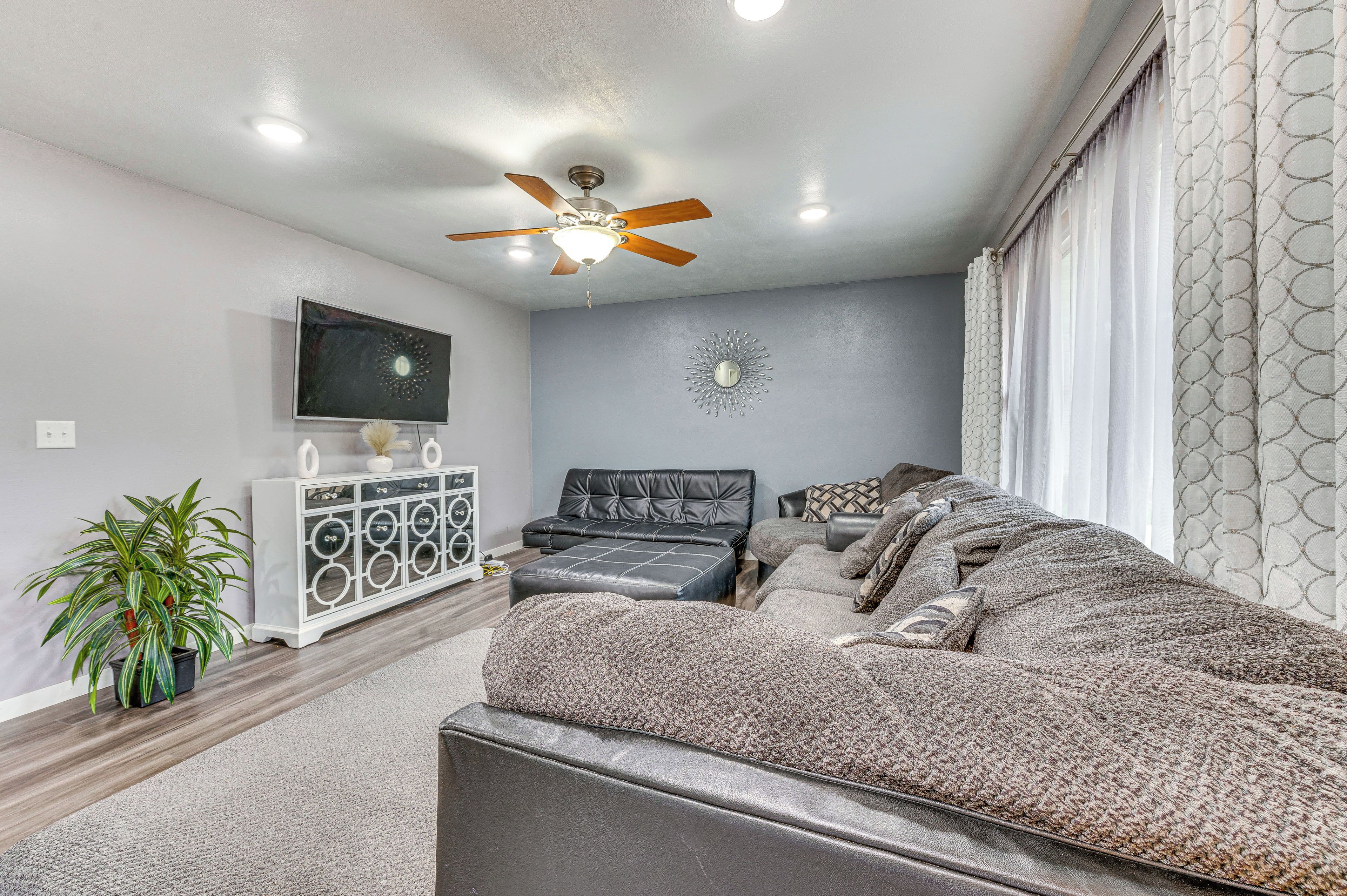 A living room with a sofa, a coffee table, a TV, a ceiling fan, and a decorative wall piece.