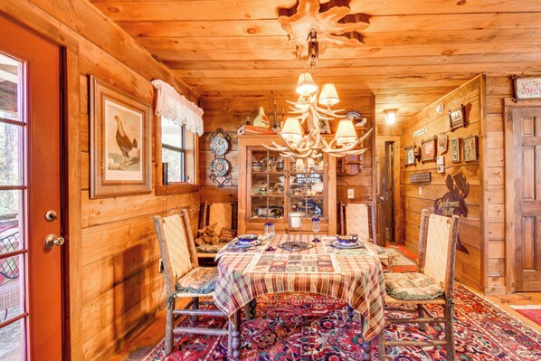Cozy cabin-style room with a dining area, chandelier, and traditional furniture.