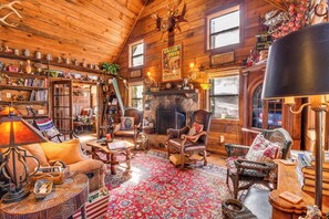 Cozy cabin-style room with a large fireplace, comfortable seating, and rustic charm.