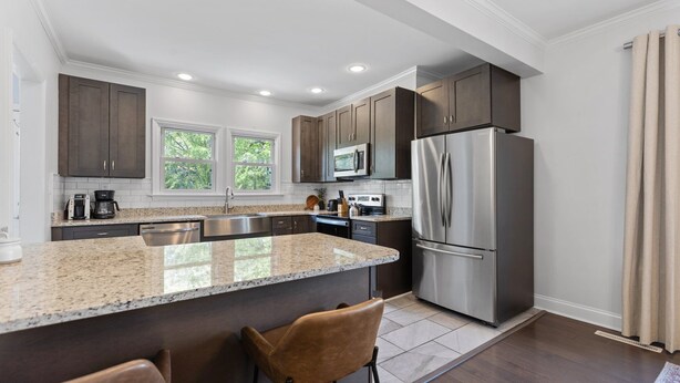 A modern kitchen with granite countertops, stainless steel appliances, and dark wood cabinets. - Adorable Bungalow, Minutes from Downtown Durham (Durham)