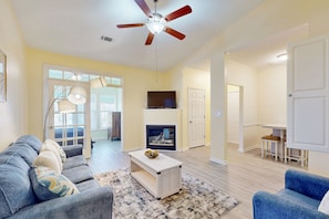 A living room with a ceiling fan, a TV, a fireplace, and a dining area.