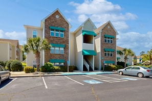 A multi-story hotel with a brick facade, green awnings, and a parking lot with handicapped parking spaces.