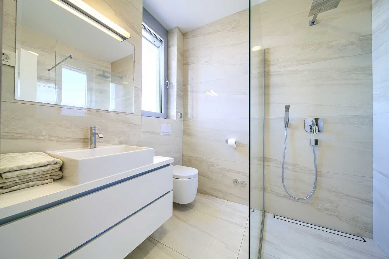 A modern bathroom with a glass-enclosed shower, a white sink, and a large mirror.
