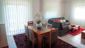 A modern living room with a dining table, chairs, a sofa, and a coffee table.