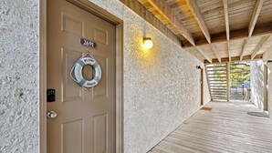 Une porte en bois avec une plaque portant un numéro, une bouée de sauvetage et un luminaire fixé au mur.