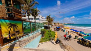 A beachside hotel with a staircase leading to a balcony, a view of the beach, and outdoor seating areas. - Flat Ponta Negra Beach Natal (Natal)