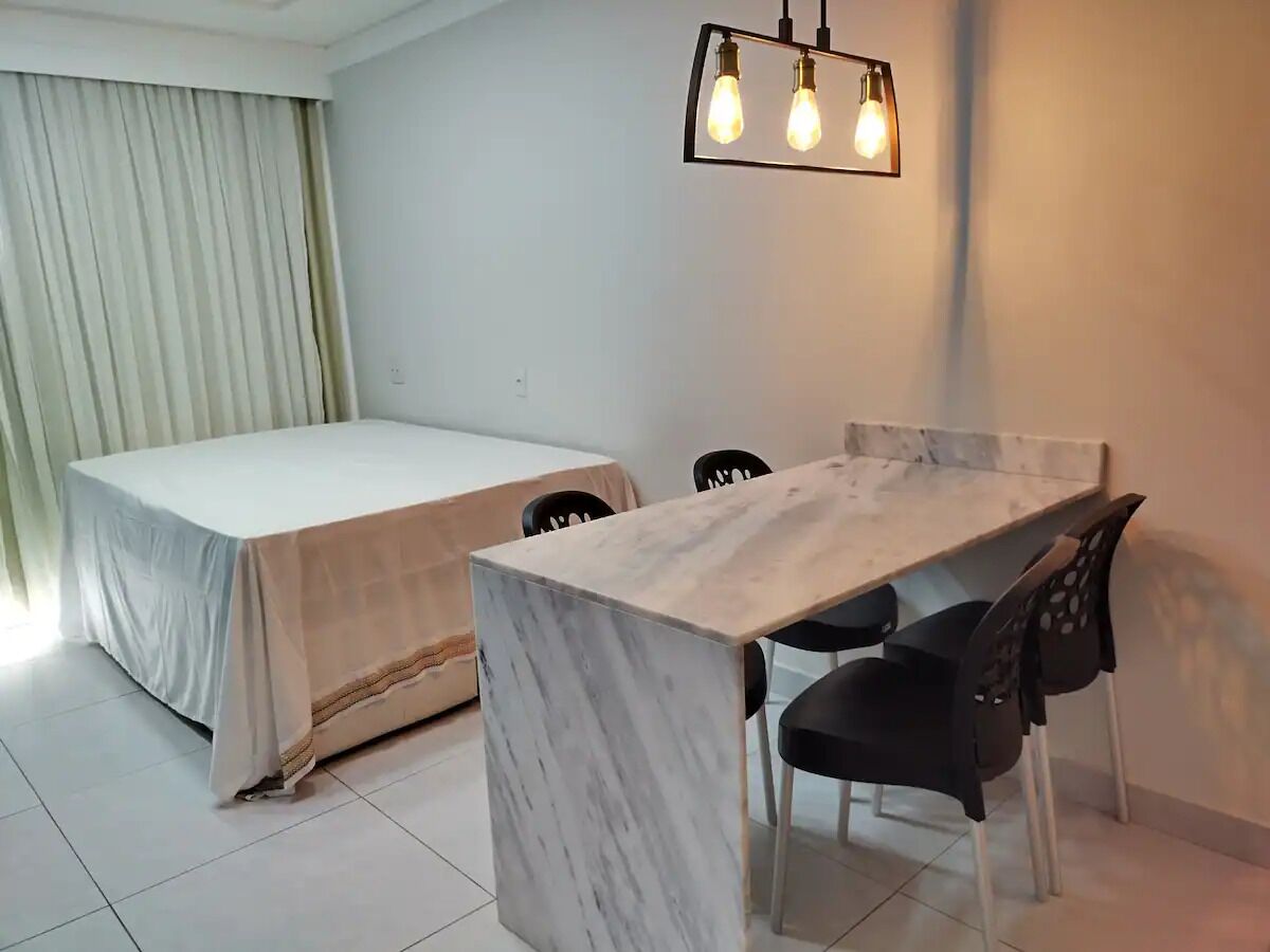 Une pièce comprenant un lit, une table à manger avec des chaises et un luminaire.