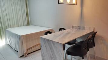 Une pièce comprenant un lit, une table à manger avec des chaises et un luminaire.