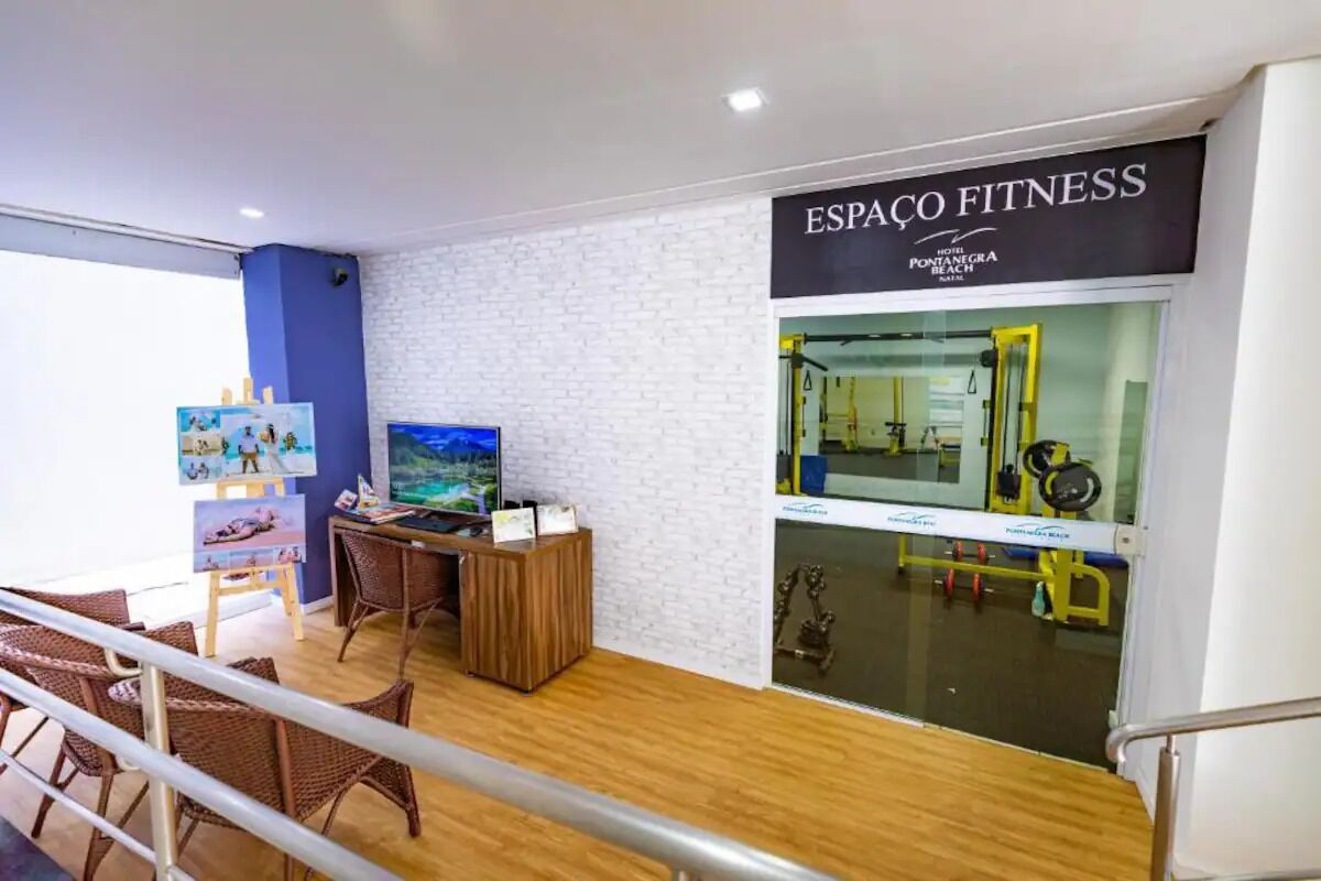 A fitness center with a reception desk, exercise equipment, and a large mirror.