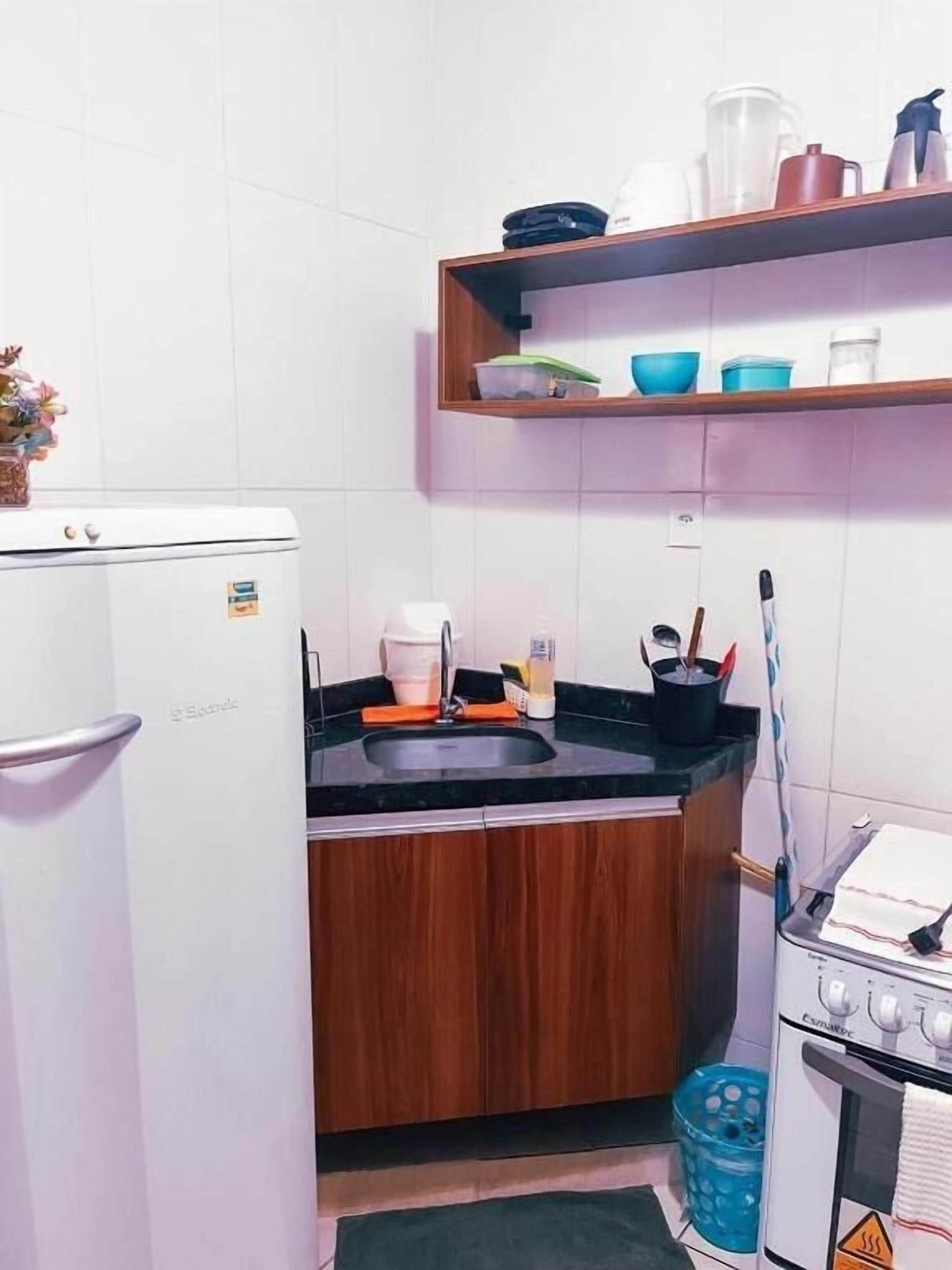 Uma cozinha compacta com geladeira, pia, fogão e armários de madeira.