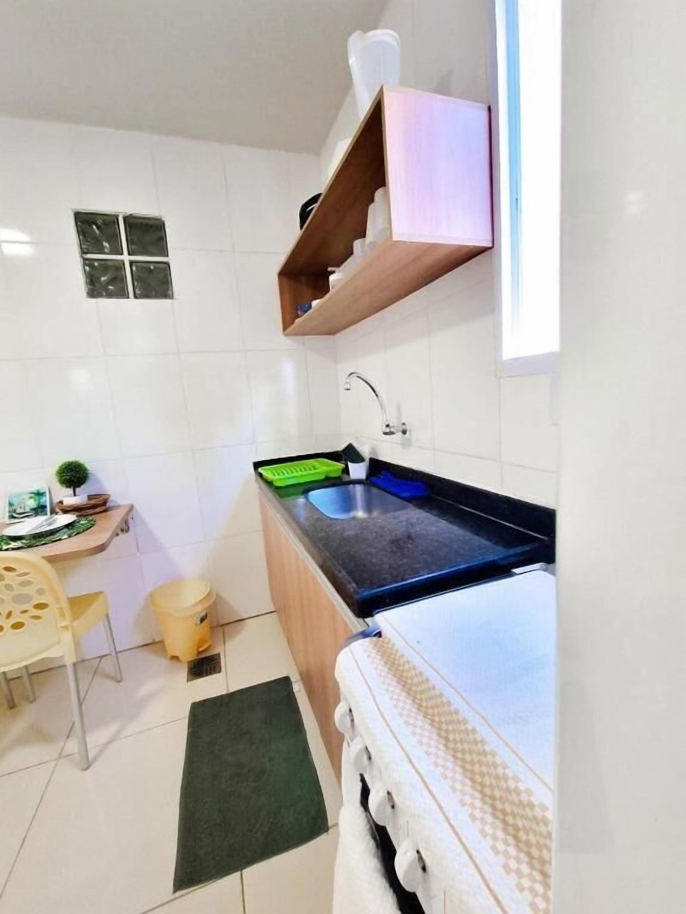 A compact kitchen with a sink, countertop, and a small dining area with a chair and table.