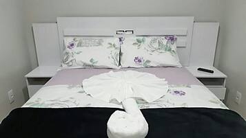 A neatly made bed with a white duvet, a black blanket, and a white decorative item resembling a fan.