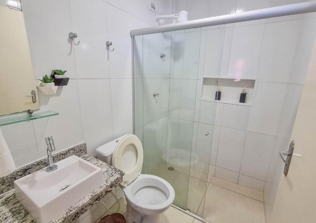 A bathroom with a glass-enclosed shower, a white sink, and a toilet.
