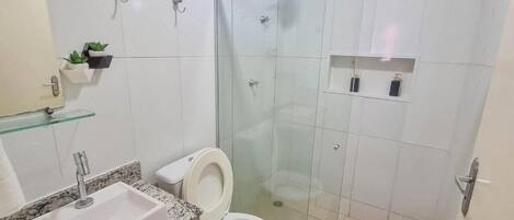 A bathroom with a glass-enclosed shower, a white sink, and a toilet.