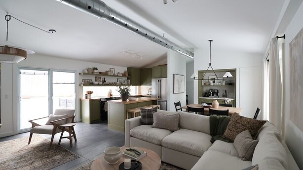 Een moderne woonkamer met een bank, salontafel en een eethoek met stoelen en een tafel.