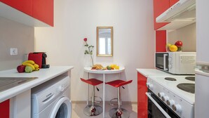 A compact kitchen with a washing machine, a microwave, and a stove. - Guilford Elegance | Corfu Old  town Apartment | fast WiFi (Corfu)