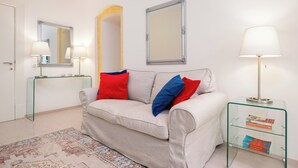 A living room with a sofa, two lamps, a glass side table, and a mirror. - Guilford Elegance | Corfu Old  town Apartment | fast WiFi (Corfu)