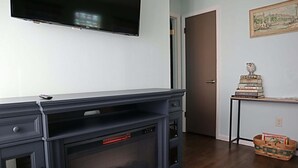 A modern living room with a fireplace, a mounted TV, and a bookshelf. - The Big Apple City View with Balcony (Dayton)