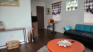 A living room with a sofa, a round table, a bookshelf, and a door leading to another room. - The Big Apple City View with Balcony (Dayton)