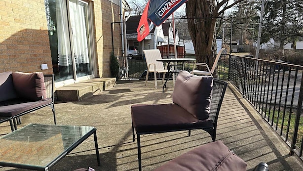 An outdoor patio with seating, a glass table, and a flag. - The Big Apple City View with Balcony (Dayton)