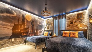 A bedroom with two beds, a chandelier, a brick wall, and a mural of a castle.