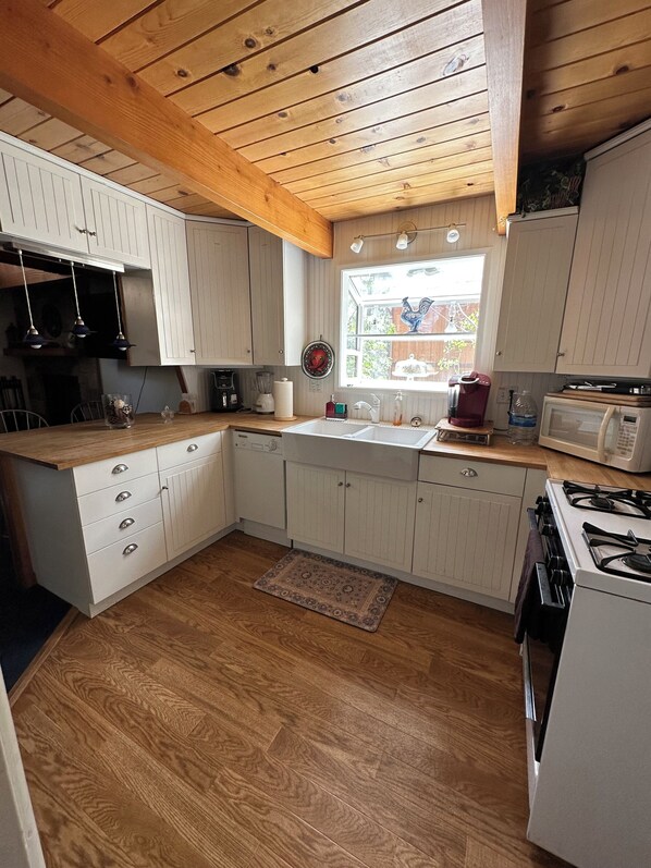 A kitchen with wooden cabinets, a built-in stove, a microwave, and a window with a view of the outside.
