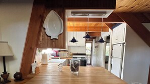 Una cocina con una isla de madera, dos sillas de mimbre, lámparas colgantes y una decoración de pared con forma de pez.