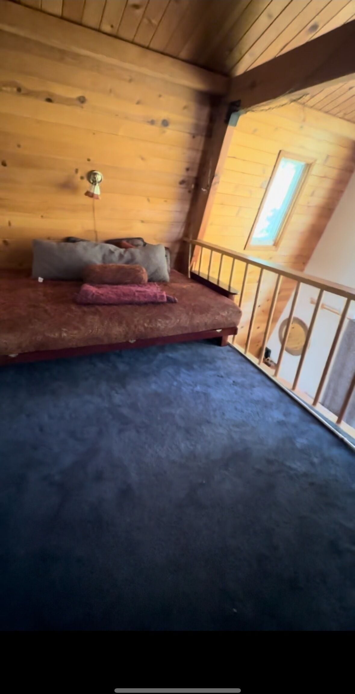 Een kamer met een bed, kussens en een klein raam.